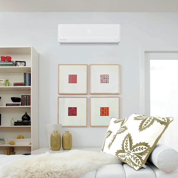 A white wall air conditioner mounted in a white bedroom