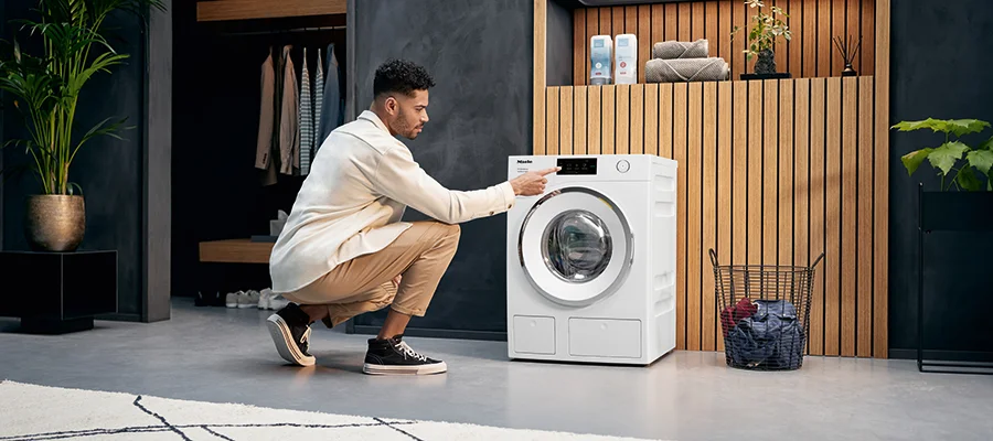 A man adjusting the settings on a white Miele dishwasher