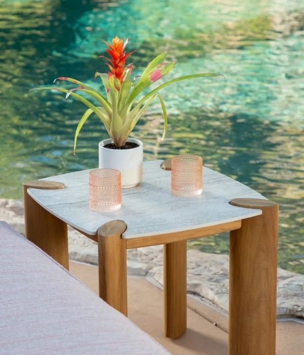 Tight shot on a Sunset West outdoor patio side table fitted with glasses and a flower in a pot