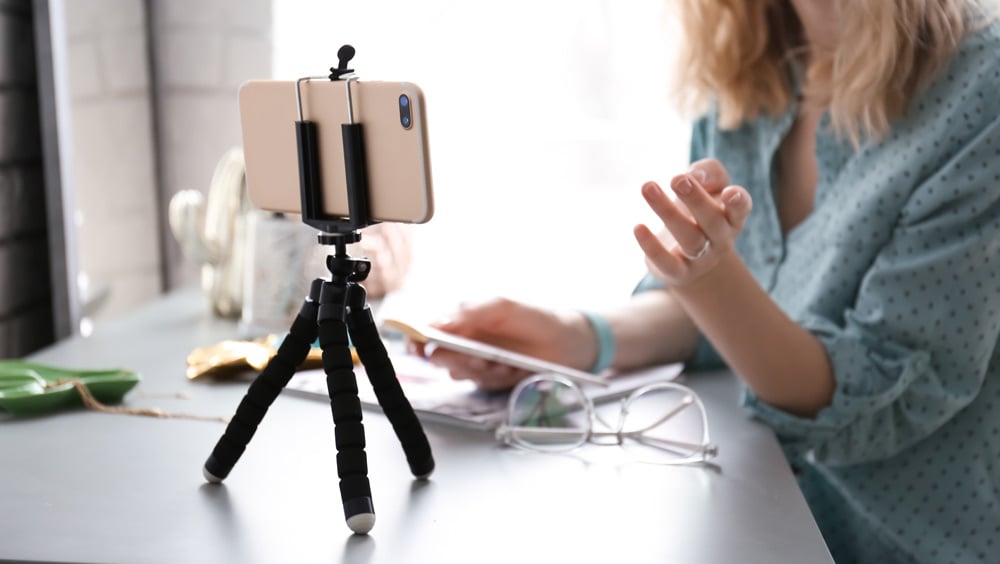 Phone on tripod with vloger behind