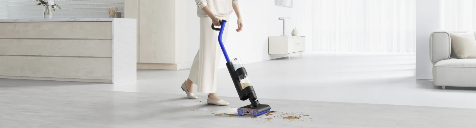 Person using the wet dry vac from Dyson on a hardwood floor cleaning up a mix of wet and dry mess showcasing the versatility of the vacuum