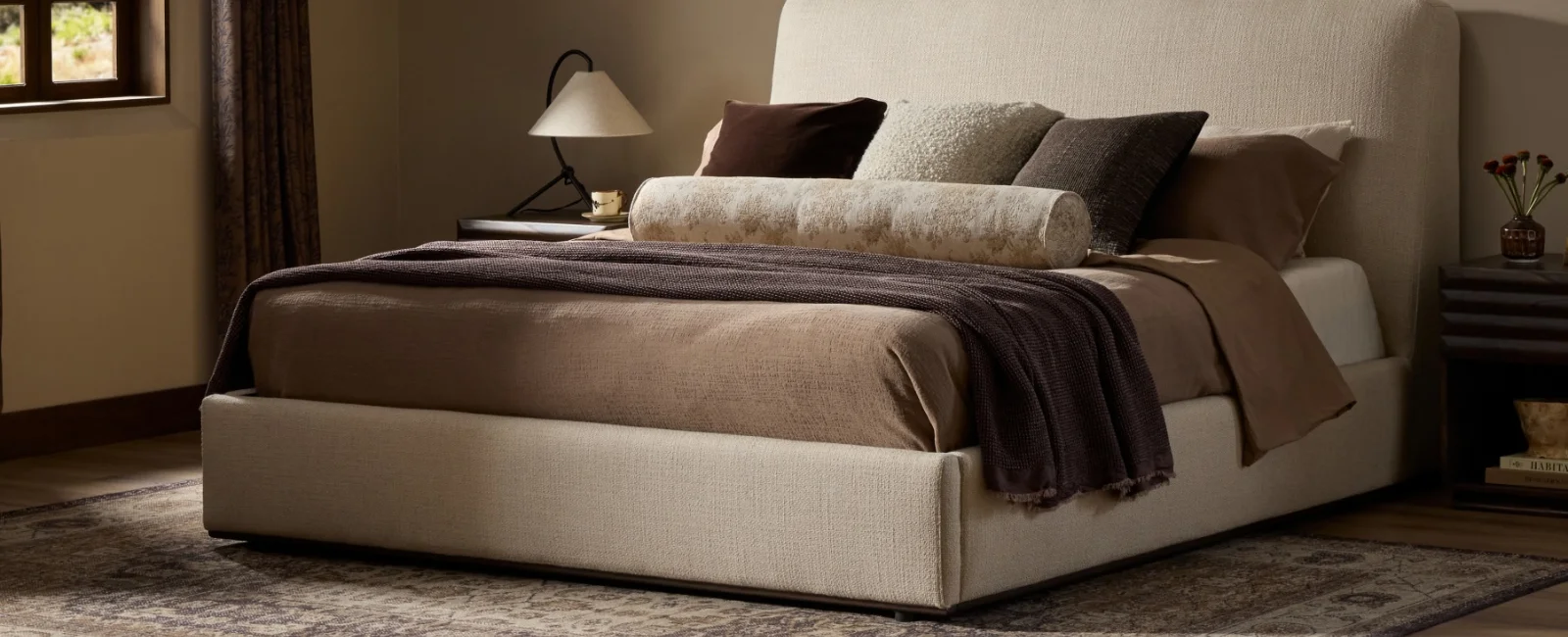 Warm, inviting bedroom interior styled for fall, with an upholstered bed, layered bedding, and matching nightstands.