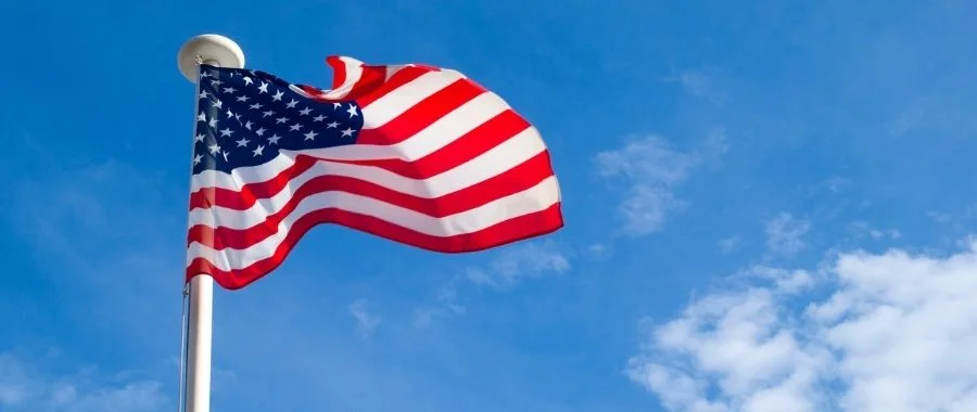 An American flag waving in front of a blue sky,