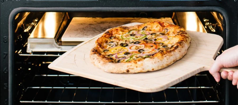 A freshly baked pizza is being taken out of the Frigidaire Gallery range.