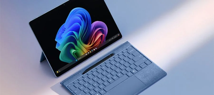 A blue Microsoft Surface Pro 2-in-1 device with a blue detached keyboard charging a Surface pen on top of a table.