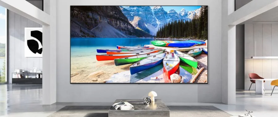 A Micro RGB TV on the wall in living room displaying red, green and blue kayaks in water near mountains.