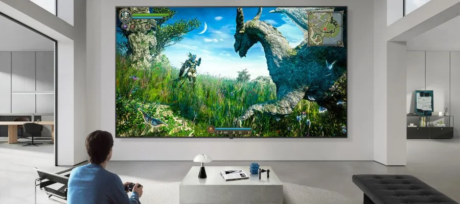 A person playing a video game on a large Micro RGB TV. A dragon dominates the colorful screen.