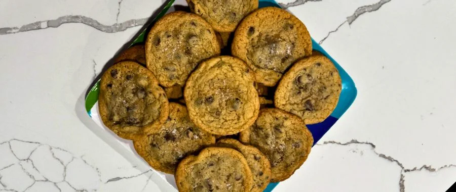 A plate of chocolate chip cookies on a marble countertop.