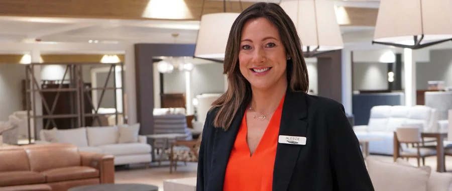 Aleece Brown in the newly-renovated furniture department at Abt. She is smiling and wearing a black blazer and red shirt
