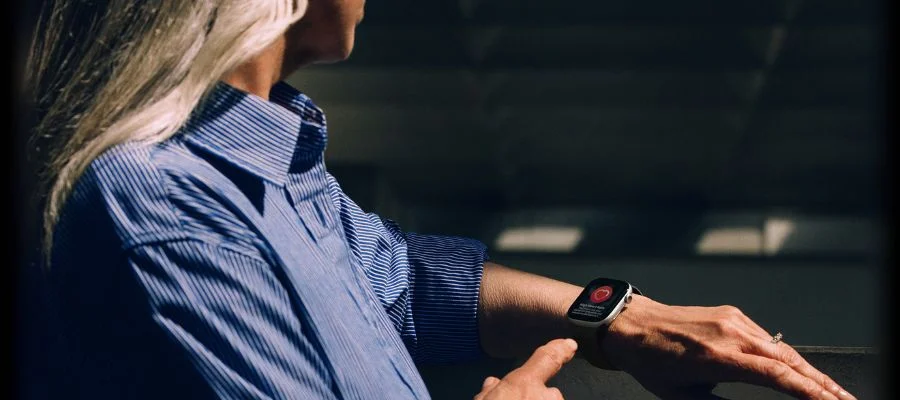 A woman wearing the Apple Watch Series 11 on her wrist. It says 'High heart rate detected'.