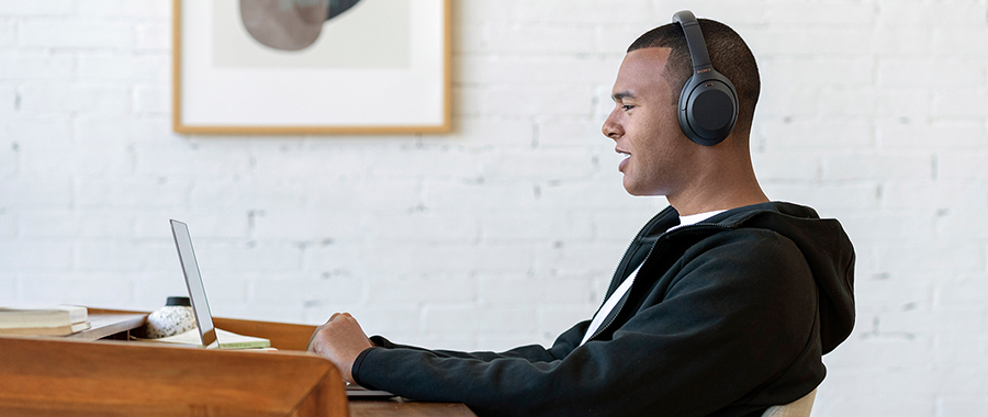 A man wearing headphones working on his laptop