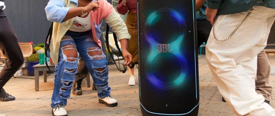 People partying outdoors beside a JBL PartyBox Speaker