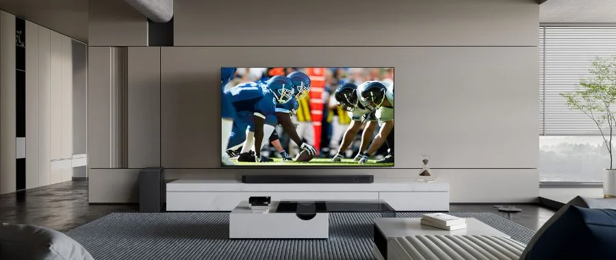 TV with a football game on mounted on a wall above a soundbar.