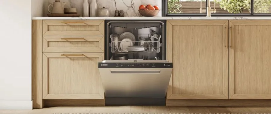 The Bosch 500 Series SHP65DM5N dishwasher partially opened in a modern kitchen.
