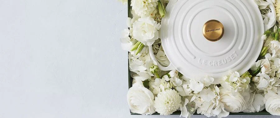 White Le Creuset Dutch oven sitting in a pile of white flowers.
