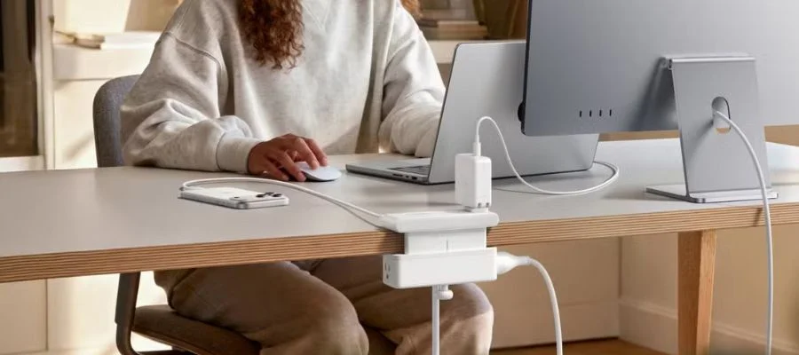 Anker Nano Power Strip attached to a wooden desk. A woman is sitting at the desk working on a laptop and a monitor at the same time.