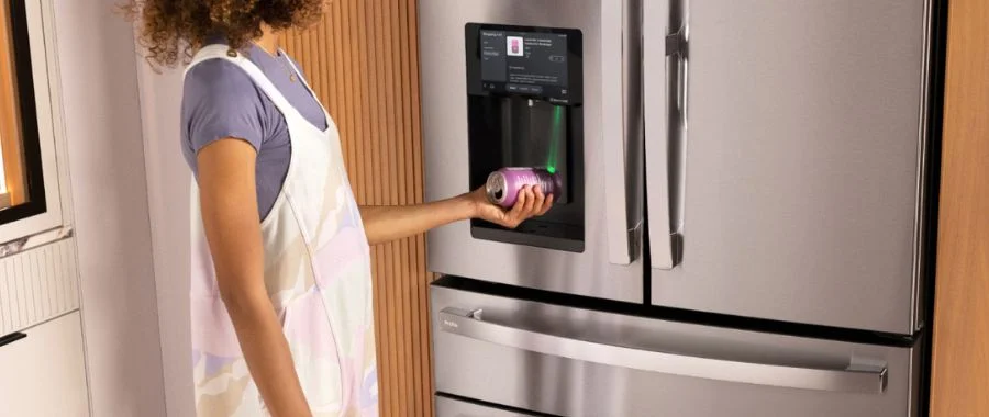 A person with curly hair holding a soda can under the barcode scanner on the GE Profile smart refrigerator.