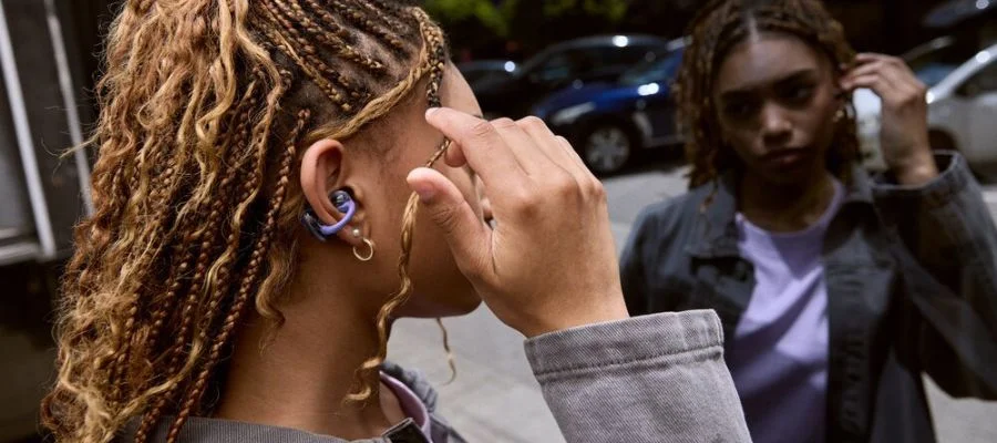 A woman wearing the new JBL SoundGear Clips as she checks her reflection in a mirror