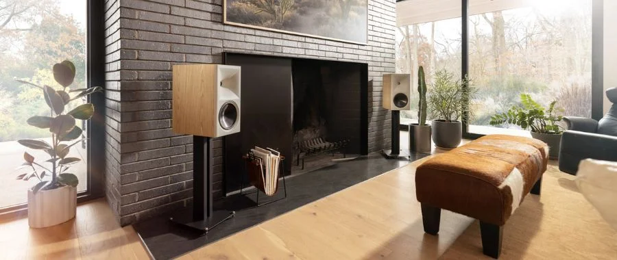 Klipsch The Nines II speakers on stands in front of a brick fireplace.