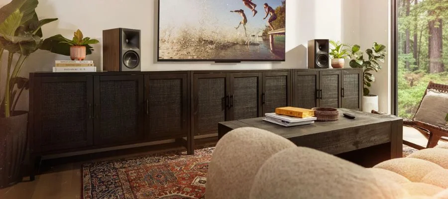 Klipsch The Sevens II speakers on a long credenza in front of a coffee table and tan quilted sofa.