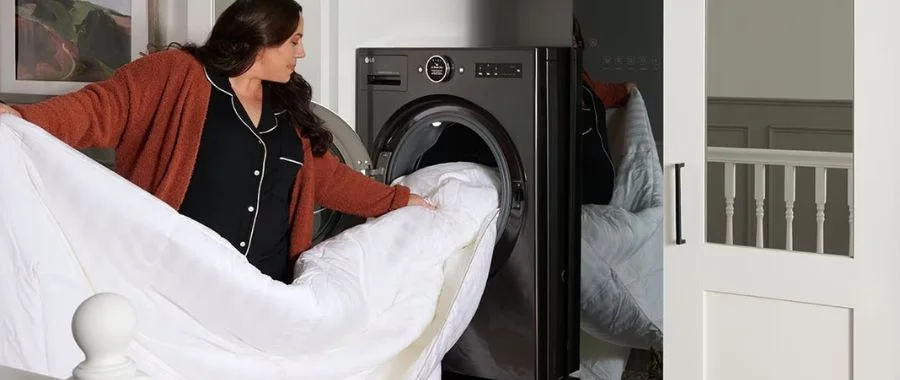 A woman loading a comforter into a dark gray LG Signature WashCombo