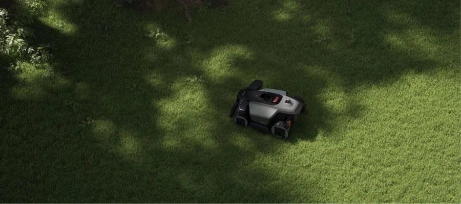 The RockMow X1 LiDAR lawn mower mowing near a small grove of trees.
