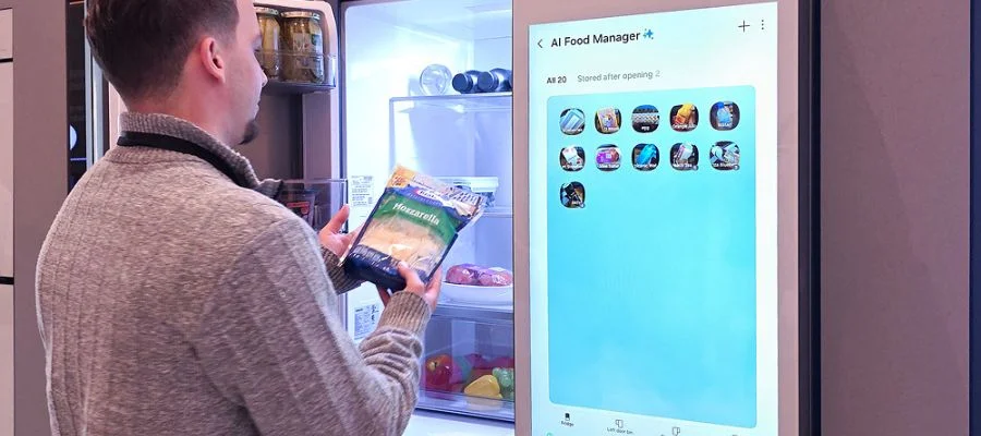 A man standing in a French door refrigerator, looking at a bag of shredded cheese. The AI Food Manager is displayed on the screen of the Samsung AI Family Hub+ refrigerator.