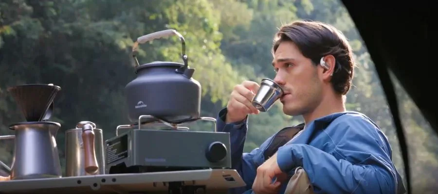 A man relaxing outside while listening with the Shokz OpenFit Pro earbuds.