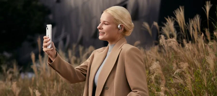 A woman talking on the phone outside while using the Shokz OpenFit Pro earbuds.