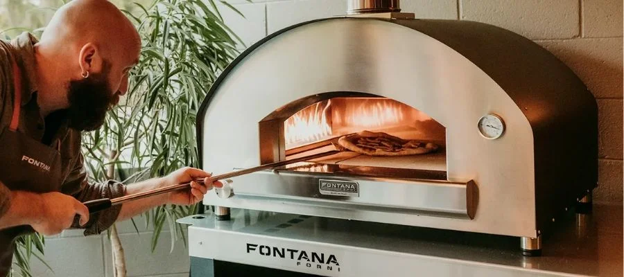A man preparing a pizza in the Fontana Firenze.