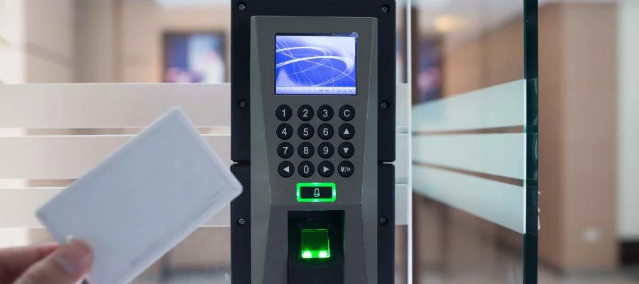 A person hovering a keycard over a security panel.