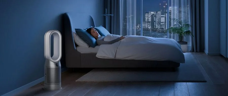 Woman asleep in bed with a Dyson air purifier in the foreground.