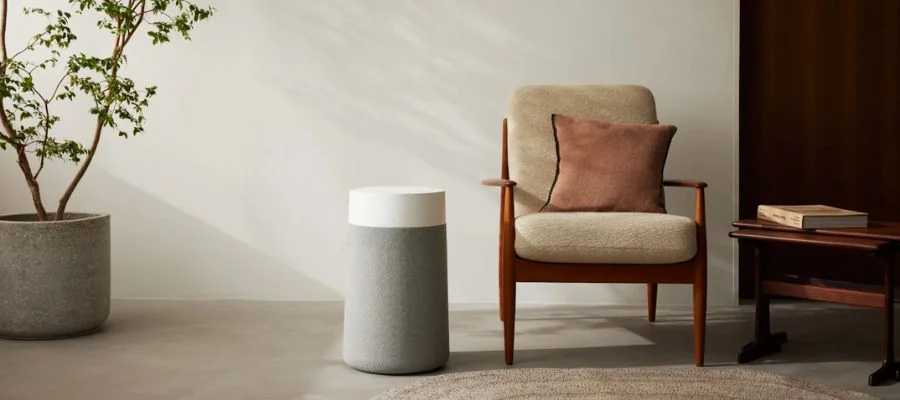 A Blueair air purifier next to an armchair and side table.