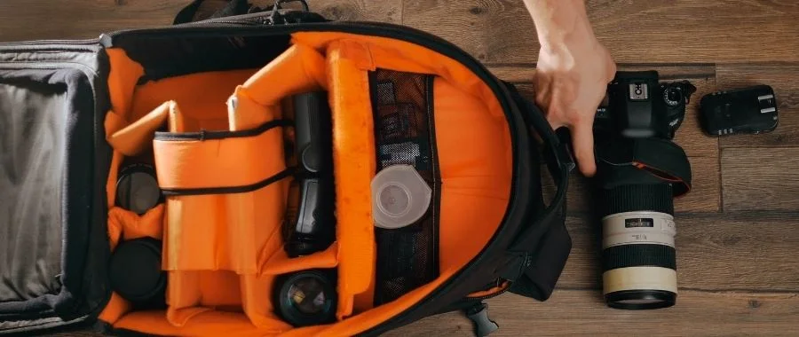Person packing a camera and lenses in a padded camera bag.