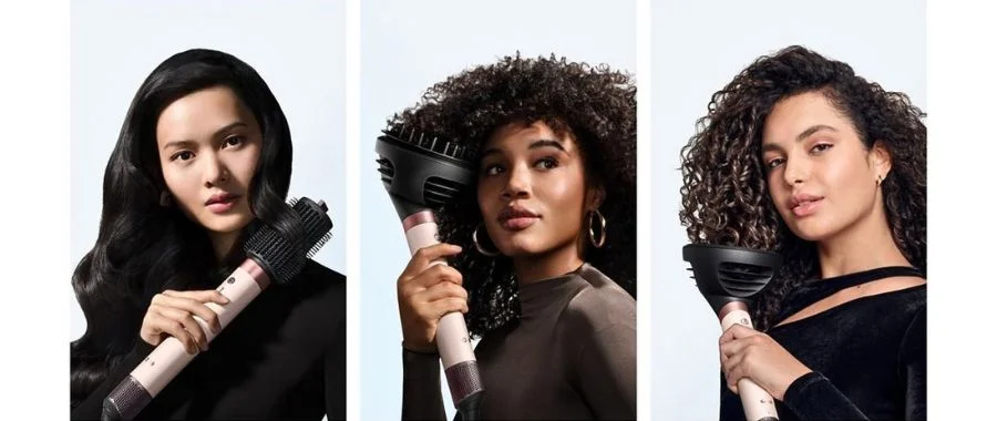 Three women using different attachments on the Dyson Airwrap Co-anda2x to style their hair,