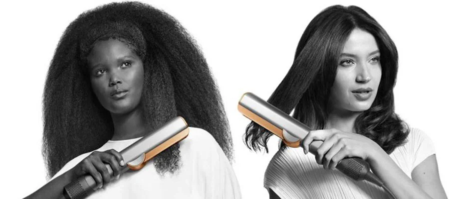 black and white photo of two women, one with curly hair and one with wavy hair, using the Dyson Airstrait