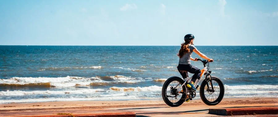 woman wearing a helmet riding a bike on the beach