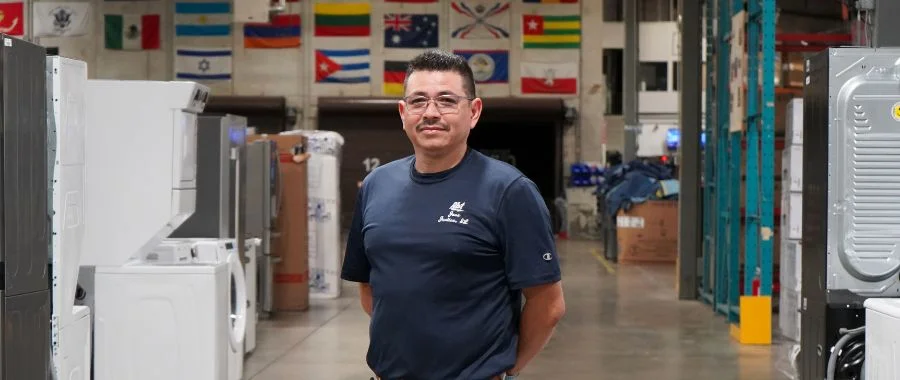 Jose Perez in the Abt warehouse standing between appliances