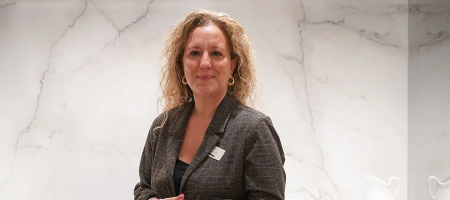 Sue Cekic smiling in the Inspiration Studio in front of a veined white backsplash