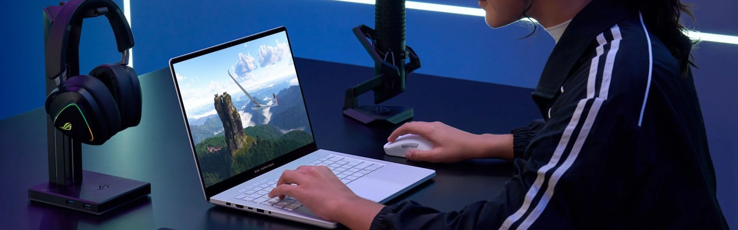 A woman gaming on a laptop and streaming with a microphone nearby.