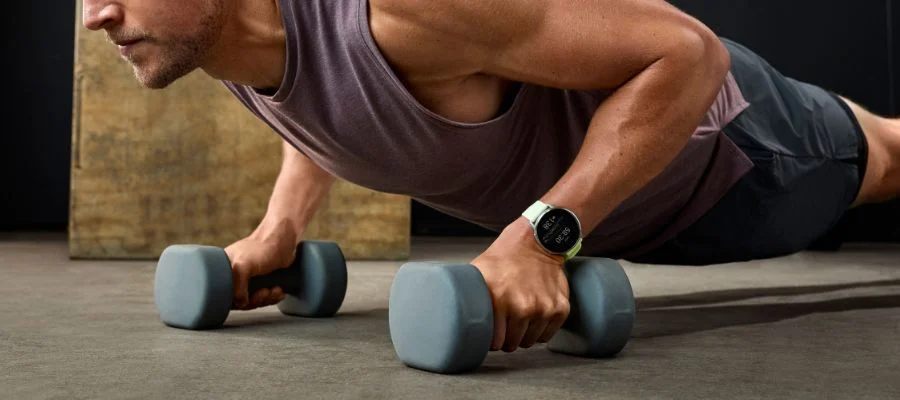 A man using weights and working out wearing the Garmin Venu 4 as he does push ups