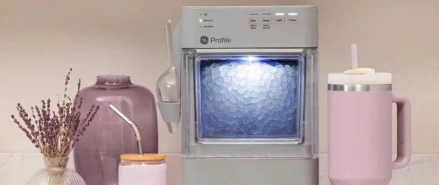 A GE Profile Opal Mini nugget ice maker beside a beverage tumbler, cup and two vases