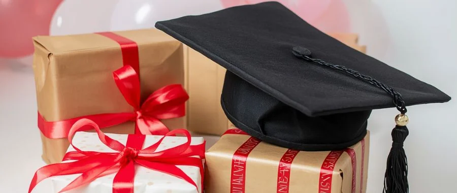 A graduation cap on top of a small pile of wrapped presents.