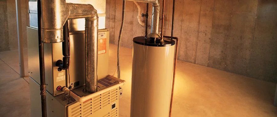A furnace next to a boiler in an empty basement.
