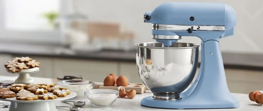Blue velvet KitchenAid stand mixer on a white kitchen counter surrounded by plates of gingerbread cookies.