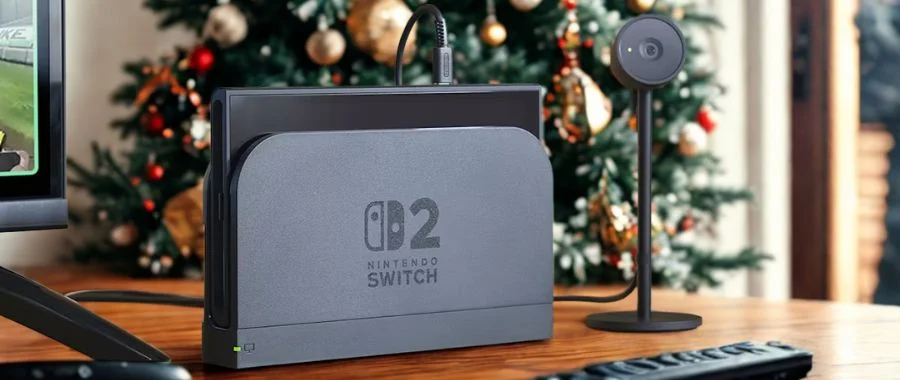 Nintendo Switch 2 and camera on a console table beside a TV. A holiday tree is in the background.
