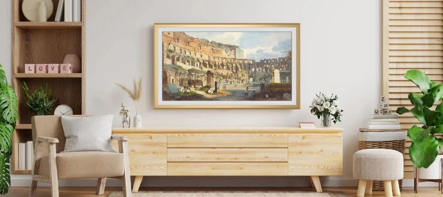 Samsung Frame TV with a gold bezel mounted above a light wood entertainment center.