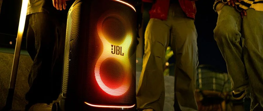 The JBL PartyBox 520 outside surround by people with a red and yellow lightshow.