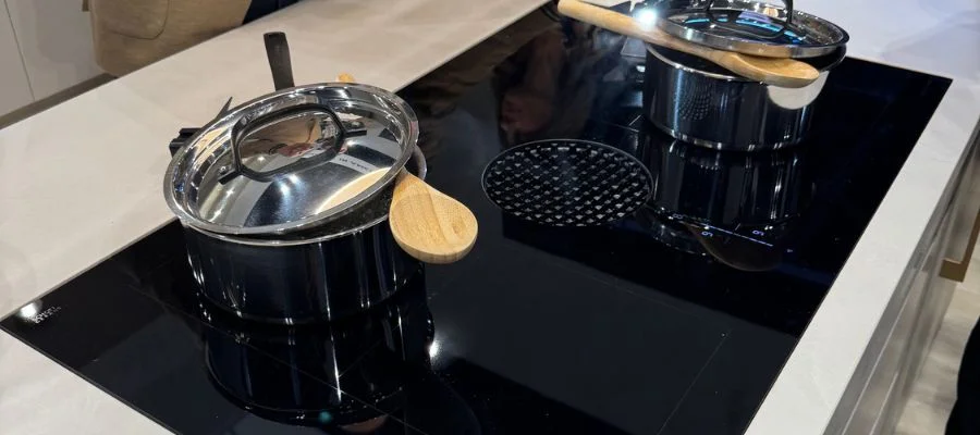 Closeup of JennAir downdraft induction cooktop with stainless steel saucepans on top.