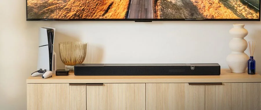 The Klipsch Flexus Core 200 soundbar atop an entertainment center beneath a TV and beside a PS5